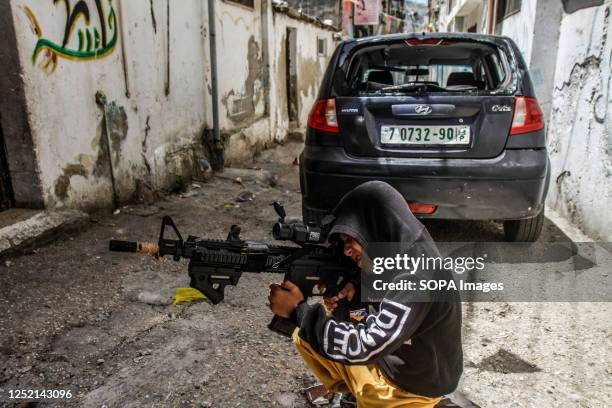 Palestinian kid plays with a plastic gun toy next to a destroyed car, after an Israeli army operation in the Askar refugee camp, east of Nablus....