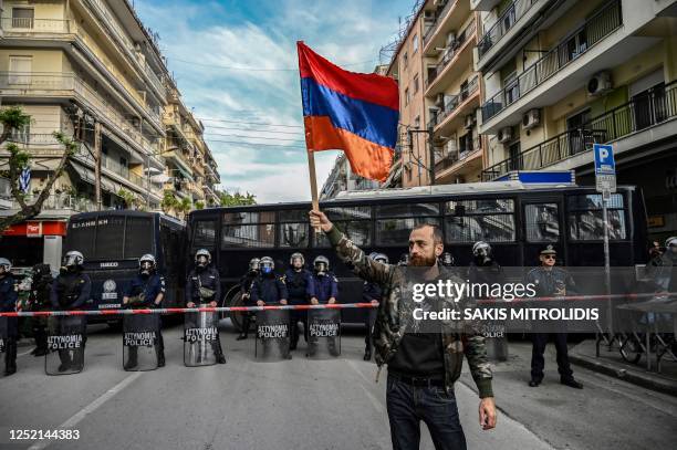 Man holds an Armenian flag in front of the anti-riot police during a rally outside the Turkish consulate to commemorate the 108th anniversary of the...