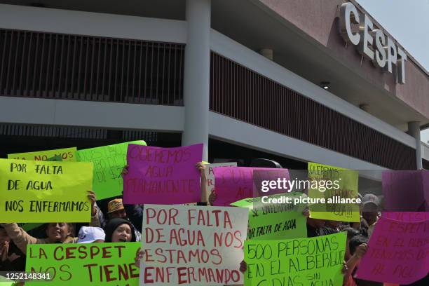 April 2023, Mexico, Tijuana: "Due to lack of water we are getting sick," reads the sign held up by a migrant during a protest in front of the...