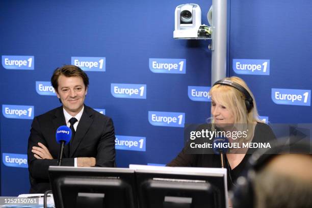 New French Finance Minister Francois Baroin , flanked by TV host Julie, waits in a studio of French Europe 1 radio on July 6, 2011 in Paris to have...