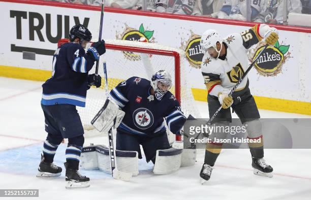 Connor Hellebuyck of the Winnipeg Jets makes a save under pressure from Keegan Kolesar of the Vegas Golden Knights in the third period of Game Four...