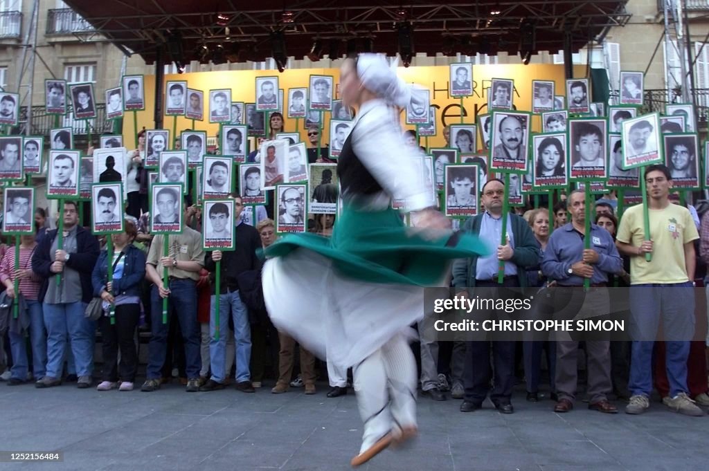 Basque Press A Basque woman in traditional suit dances in front of people holding ...