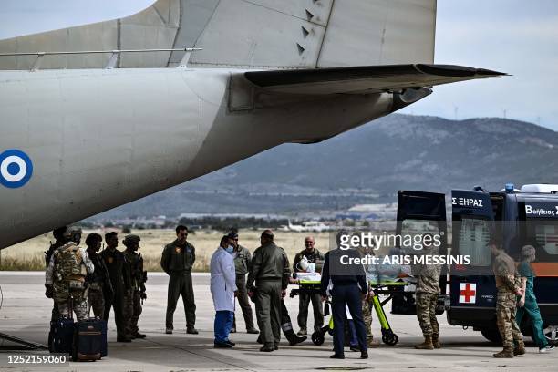Soldiers carry a Greek national with leg injuries into an ambulance after his evacuationfrom Sudan with a military C-27 plane at the military airport...