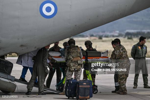 Soldiers carry a Greek national with leg injuries into an ambulance after his evacuationfrom Sudan with a military C-27 plane at the military airport...