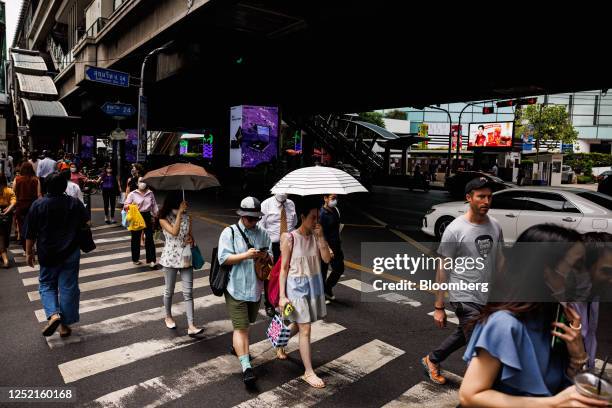 Pedestrians use umbrellas to shield themselves from the sun in Bangkok, Thailand, on Tuesday, April 25, 2023. Thailand's government will cut power...