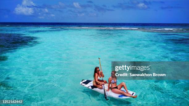 two young caucasian teens on a paddle board on an exotic island in fiji, pacific ocean - fiji smiling stock pictures, royalty-free photos & images