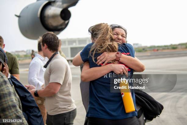 In this handout provided by the U.S. Navy, U.S. Government personnel from the U.S. Embassy in Sudan embrace as they evacuate to Camp Lemonnier on...