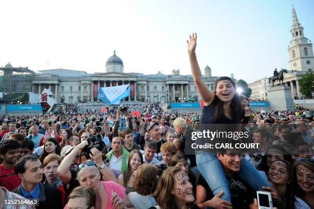 People cheer in Trafalgar Square as they attend a ceremony to unveil of the London 2012 gold, silver and bronze medals, to mark the one-year...