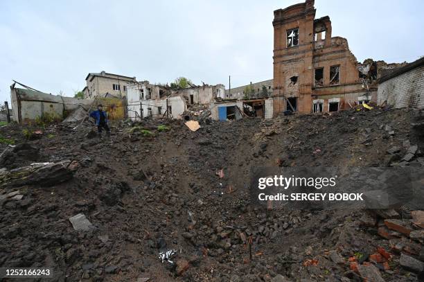 Local resident looks at an explosion crater next to the local history museum destroyed following Russian missile strike in the town of Kupiansk,...