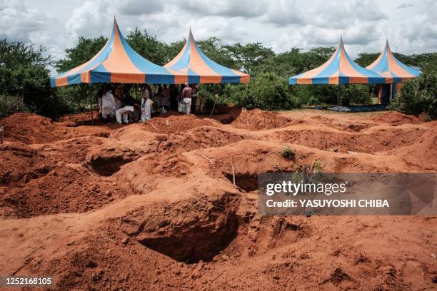 Workers take shelter while digging the ground to exume bodies from the mass-grave site in Shakahola, outside the coastal town of Malindi, on April...