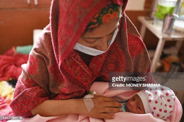 This photograph taken on April 25, 2023 shows Manu Bala holding her newborn daughter inside a maternity ward of a civil hospital in Dehra, in Kangra...