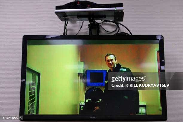 Jailed Russian opposition figure Alexei Navalny is seen on a screen via a video link from his penal colony before a hearing over the extremism...