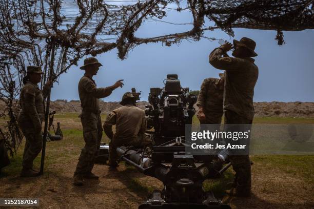 Members of the United States army inspects a 105 millimeter howitzer cannon after rounds were fired during a live fire drill by combined forces of...