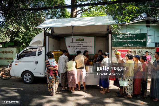 People line up to receive low-cost or free cooking oil from a charity sponsor on the street as the daily life continues in Yangon, Mynmar on April 4,...