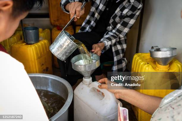 People line up to receive low-cost or free cooking oil from a charity sponsor on the street as the daily life continues in Yangon, Mynmar on April 4,...