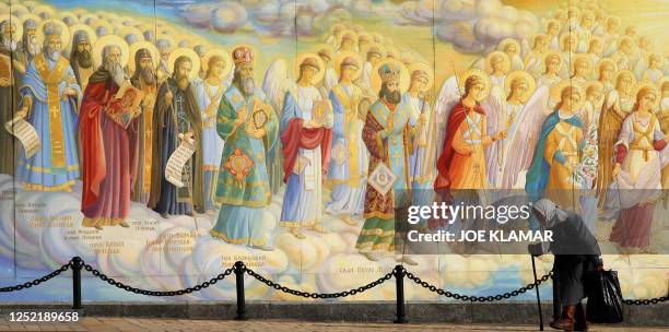 An elderly woman passes wall of St. Michael's church in Michail's square in Kiev on 29 September 2007. That day, seventy couples took part in a mass...