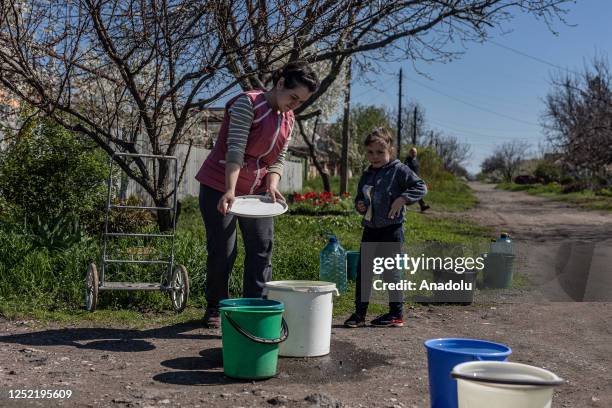 Mother and daughter fill water to water bottles and buckets from a Ukrainian Emergency Service water tanker, which travels through the streets of...