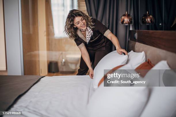 maid changing bed linen on the bed in a hotel room - hotel housekeeping stock pictures, royalty-free photos & images