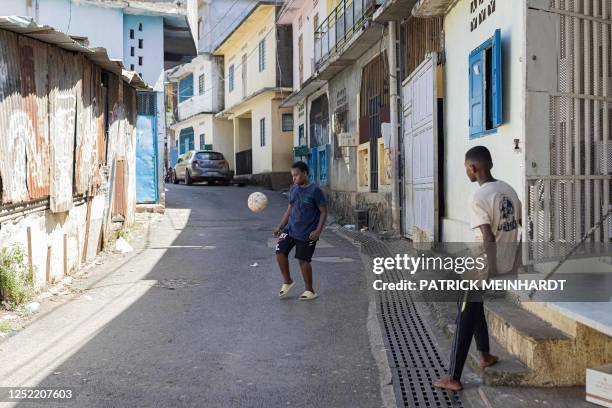 Child plays football in the street in Kaweni, Mamoudzou, on the island of Mayotte on April 26, 2023. - Authorities in Mayotte were expected to launch...