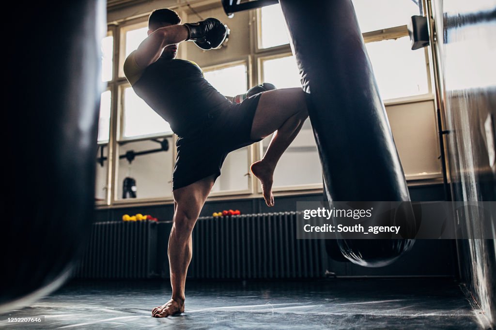 Hombre kick boxeador entrenamiento solo en el gimnasio