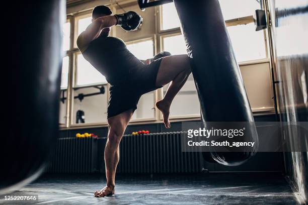 hombre kick boxeador entrenamiento solo en el gimnasio - mixed martial arts fotografías e imágenes de stock