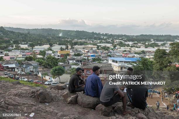 Boys speak as they sit on a hill overlook the village of Kaweni, near Mamoudzou, on the island of Mayotte on April 26, 2023.