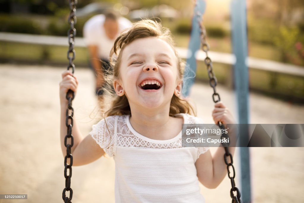 Smiling girl playing on the swing