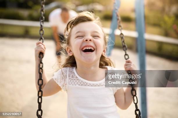 smiling girl playing on the swing - playground stock pictures, royalty-free photos & images