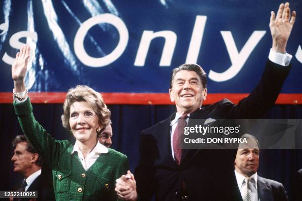 President and Republican presidential candidate Ronald Reagan and his wife Nancy wave to supporters at an electoral meeting in November 1984, a few...