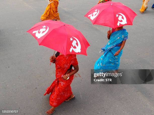 Communist Party of India party supporters hold party umbrellas with the sickle and hammer during an election rally in Agartala on April 21, 2009....
