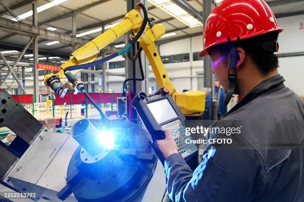 Worker controls a robot arm for welding at Jinluo Water Co LTD in Linyi city, East China's Shandong province, April 26, 2023. Jinluo Water Co., Ltd....