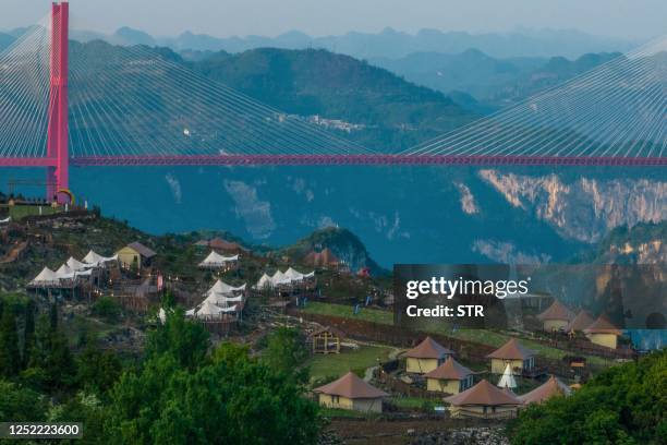 This aerial photo taken on April 25, 2023 shows houses built nearby a cliff at a campground in Bijie, in China's southwestern Guizhou province. /...