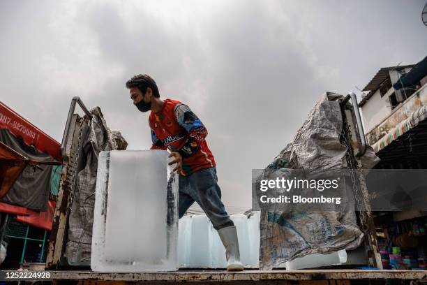 Workers unload blocks of ice at a wet market during a heatwave in Bangkok, Thailand, on Thursday, April 27, 2023. Thailand's government will cut...