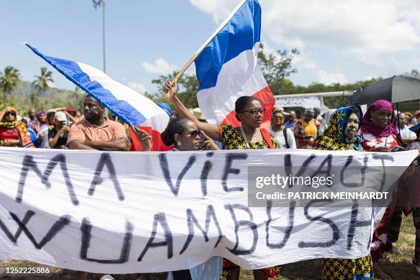 People wave French flags as they hold a banner that reads "My life is Wuambush" during a rally in support of Operation Wuambushu in Chirongui, on the...