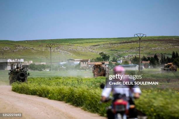 Man rides a motorcycle near a Turkish and Russian military vehicles during a patrol in Rumaylan , in Syria's northeastern Hasakeh province bordering...