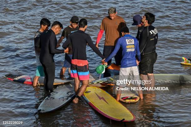 People pray before surfing the waves of a tidal bore known as "Pororoca" at Mearim River in Arari, Maranhao state, Brazil, on April 22, 2023. -...