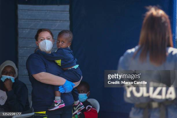 Migrant child with a rescuer during the checks after disembarking in Naples from the Geo Barents rescue ship, after being saved from a shipwreck in...