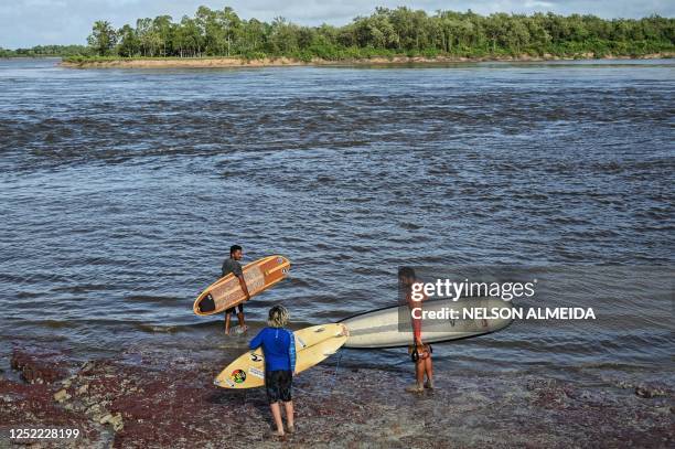 People prepare to surf the waves of a tidal bore known as "Pororoca" at Mearim River in Arari, Maranhao state, Brazil, on April 22, 2023. - Pororoca,...
