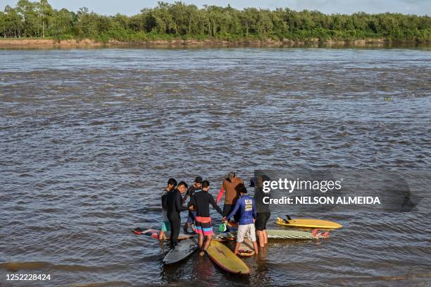 People pray before surfing the waves of a tidal bore known as "Pororoca" at Mearim River in Arari, Maranhao state, Brazil, on April 22, 2023. -...