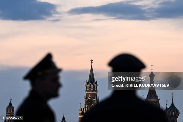 Russian servicemen stand with the Kremlin's Spasskaya tower and Saint Basil's cathedral before the Victory Day military parade rehearsal in central...
