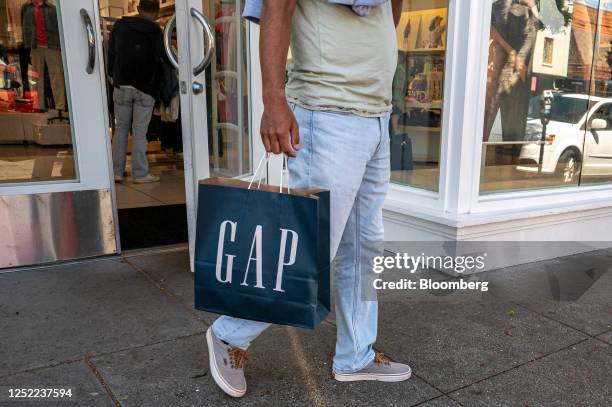 Shopper carries a Gap bag outside a store in San Francisco, California, US, on Thursday, April 27, 2023. Gap Inc. Will eliminate about 1,800...