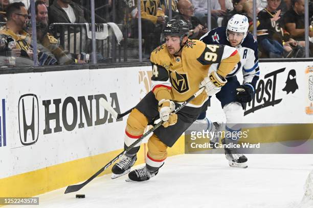 Brayden Pachal of the Vegas Golden Knights skates with the puck ahead of Adam Lowry of the Winnipeg Jets in the first period of Game Five of the...
