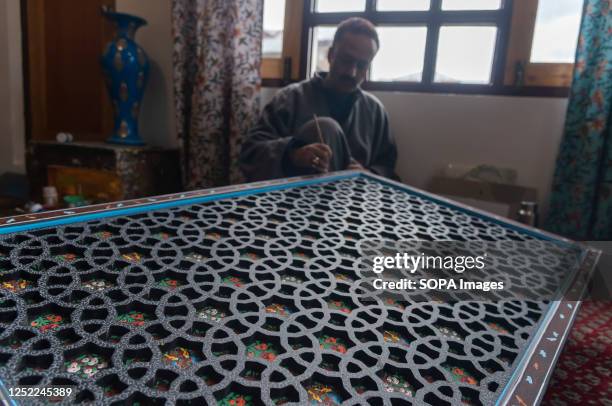 Maqbool Jan, an award winning artisan is seen working on a wall frame designed with Paper Mache at his workshop in Srinagar. Papier-Mache...