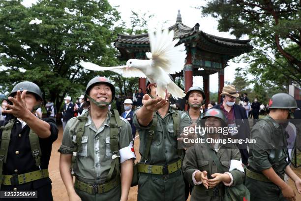 South Korean performers wearing military uniforms release pigeons during a ceremony to mark the 70th anniversary of the Korean War in Cheorwon, near...