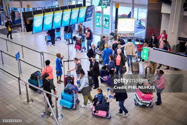 Travelers waits at Schiphol Airport, on April 28, 2023. - The May holiday provides a major test for Schiphol, many people travel to their holiday...