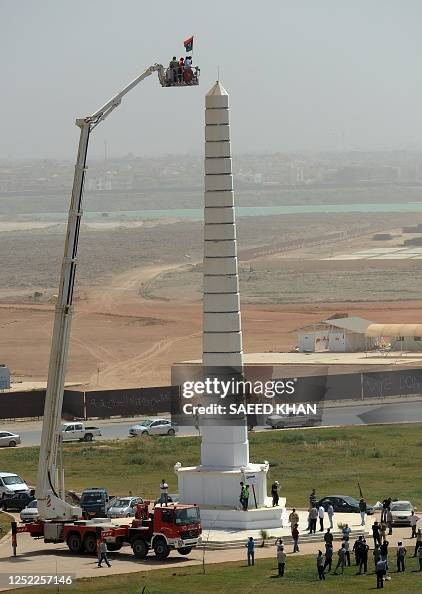 Libyan rebel fighters and their supporters hoist a former Libyan ...