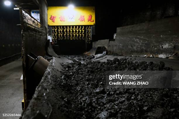 This photo taken on April 26, 2023 shows mined coal on a conveyor belt while underground at the Xiaobaodang coal mine near Yulin, in China's northern...