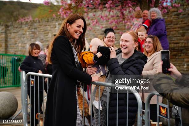 Lucy Williams, from Aberfan, holds her son Daniel Williams, one, as he takes the handbag of the Princess of Wales, during her visit with her husband...