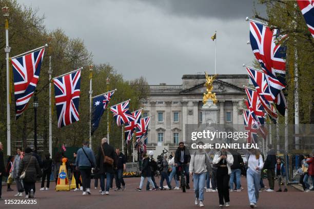 People walk beneath flags of the Union and Commonwealth on The Mall, looking towards Buckingham Palace, in central London, on April 28, 2023 ahead of...