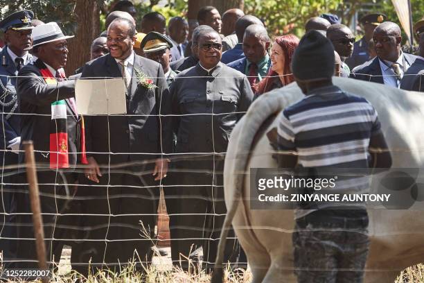 Zimbabwe President Emmerson Mnangagwa talk to eSwatini monarch, King Mswati III as they look on a bull being cleaned during the 63rd edition of the...